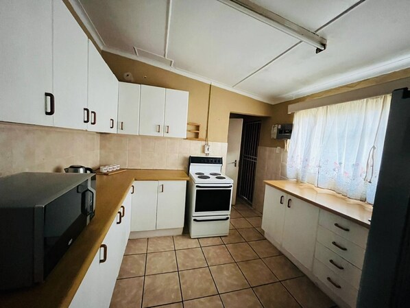A compact kitchen with white cabinets, a stove, and a microwave.