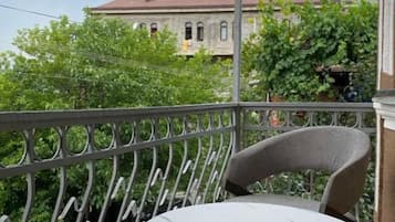 Un balcon avec une table ronde et des chaises, donnant sur un bâtiment doté d’un dôme jaune et d’un toit rouge.