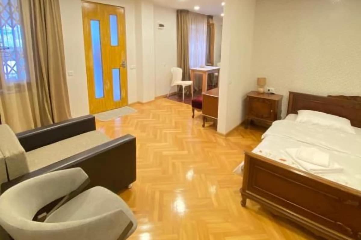 A hotel room with a bed, a sofa, a chair, a desk, and a nightstand.