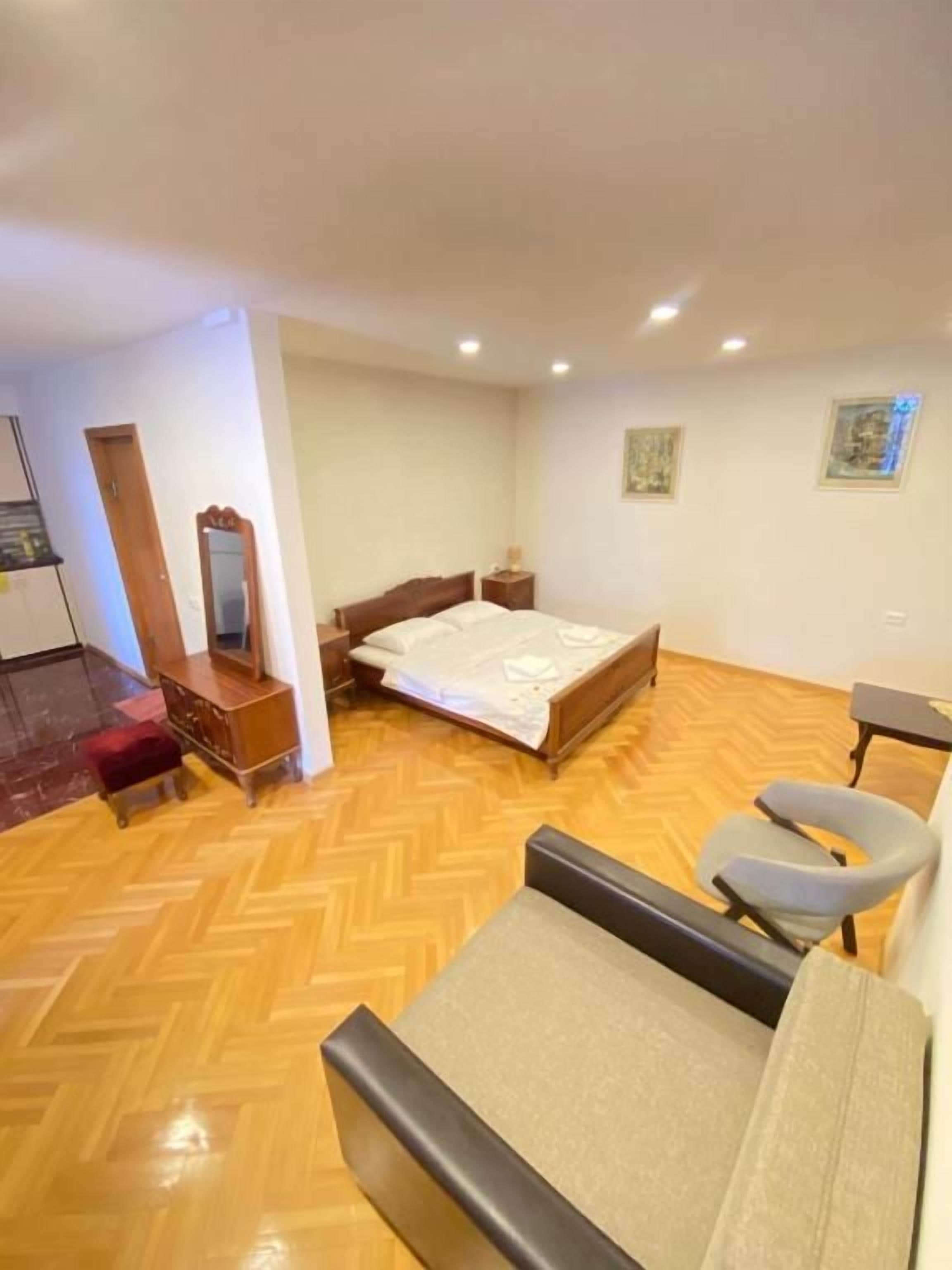 A room with a bed, a chair, a desk, and a mirror.