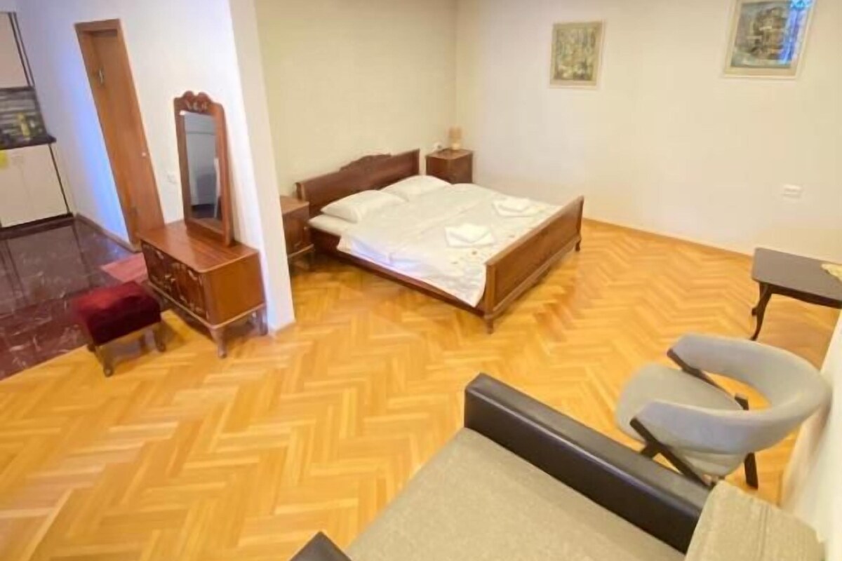 A room with a bed, a chair, a desk, and a mirror.