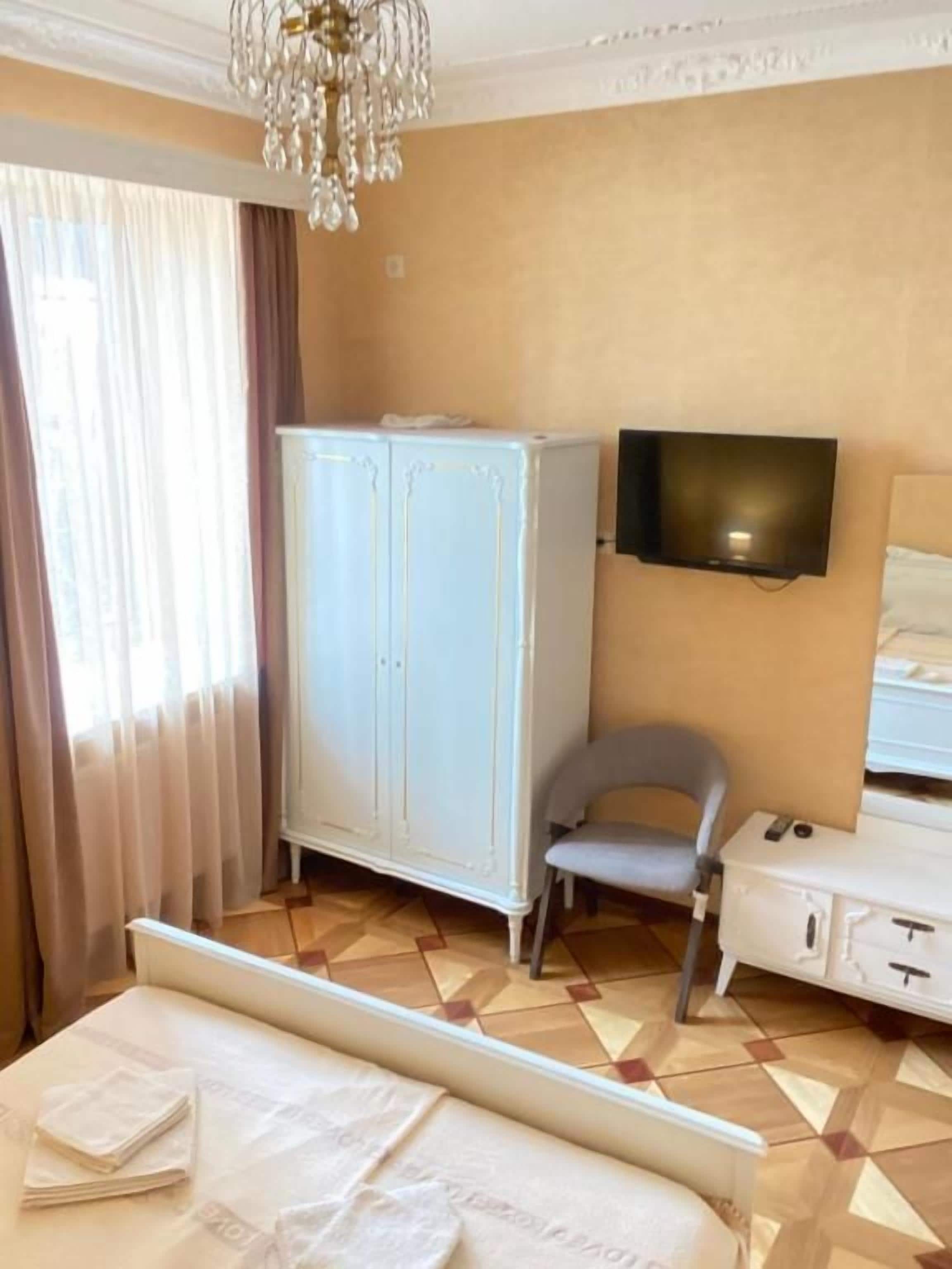 Una habitación de hotel con una cama, armario, televisor y escritorio.