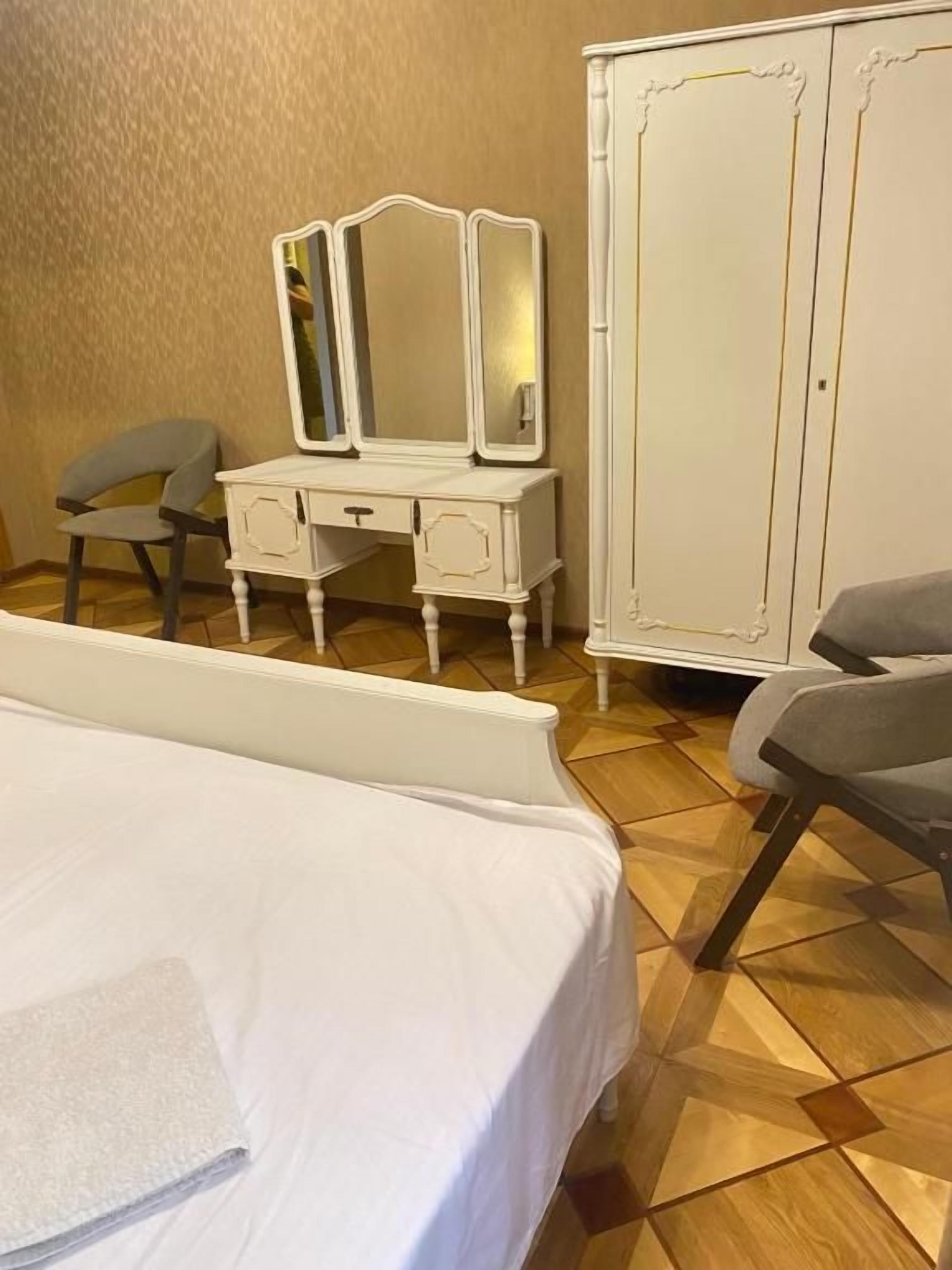 Een hotelkamer met een bed, een kaptafel met spiegel en een kledingkast.