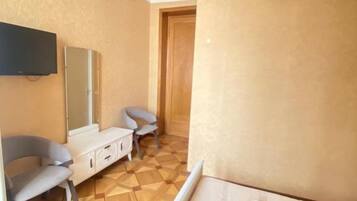 A hotel room with a bed, a TV, a desk, and two chairs.