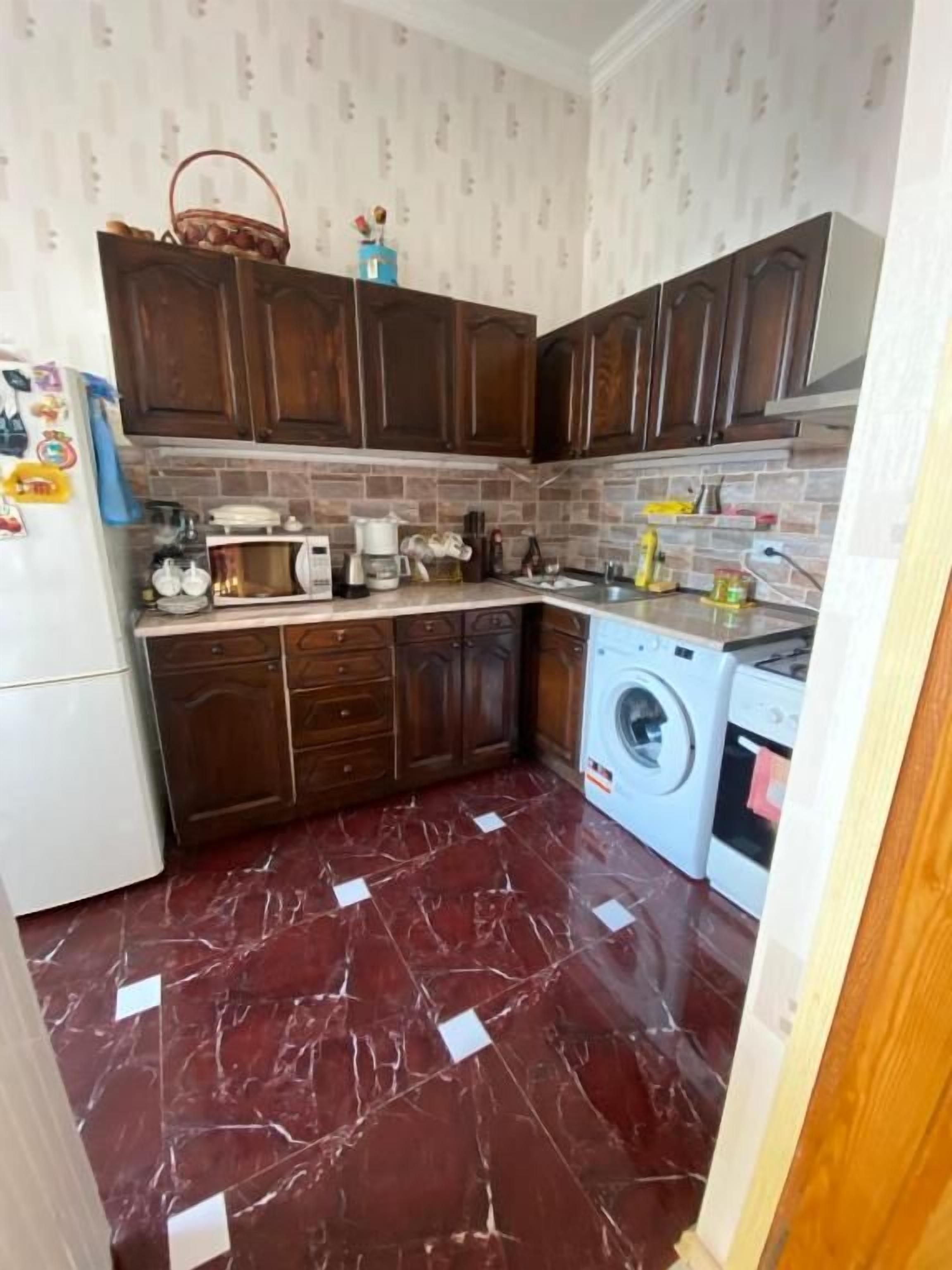 Una cocina compacta con armarios de madera oscura, lavadora y microondas.