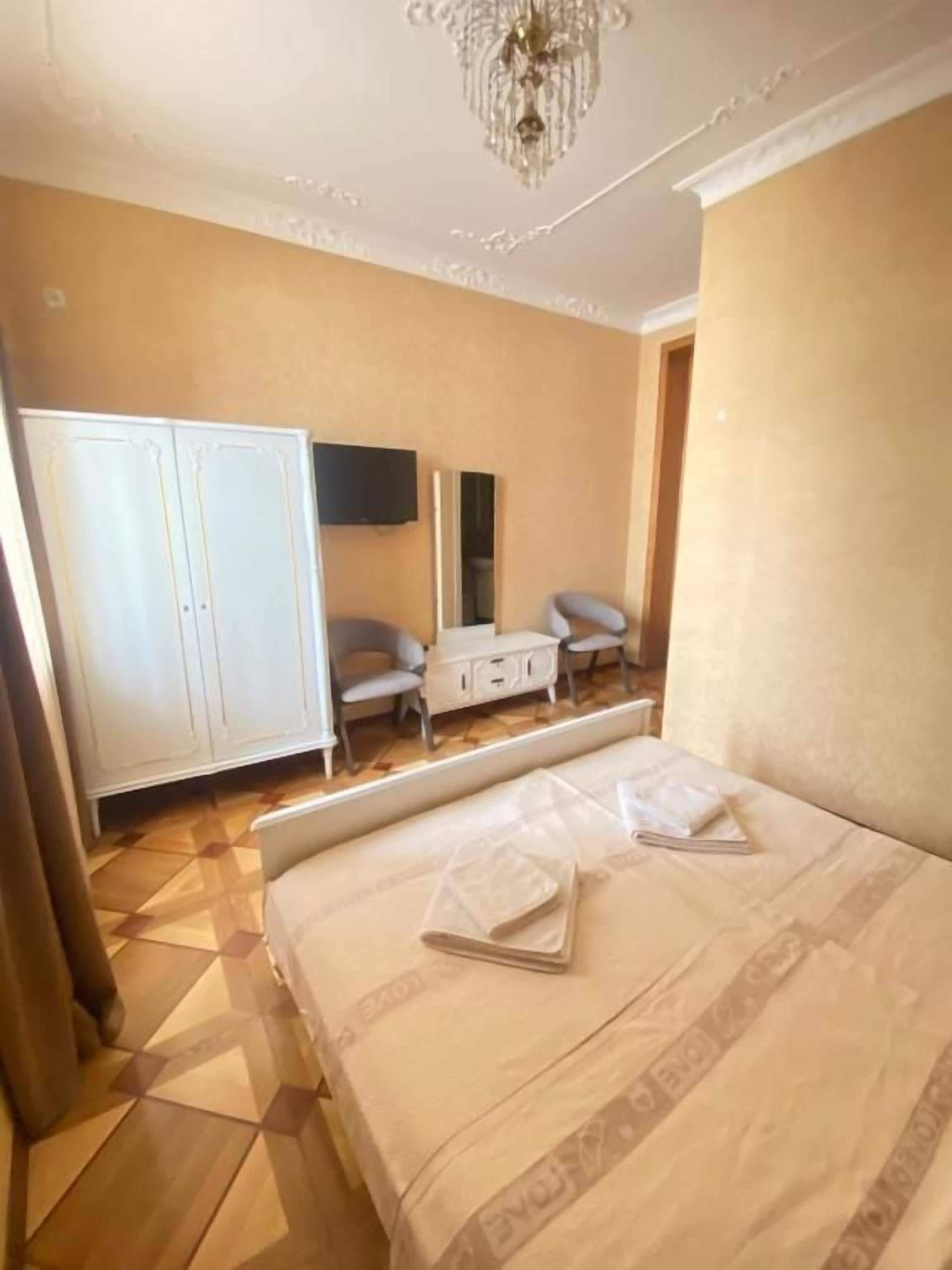 A hotel room with a bed, a wardrobe, a desk, and a chair.