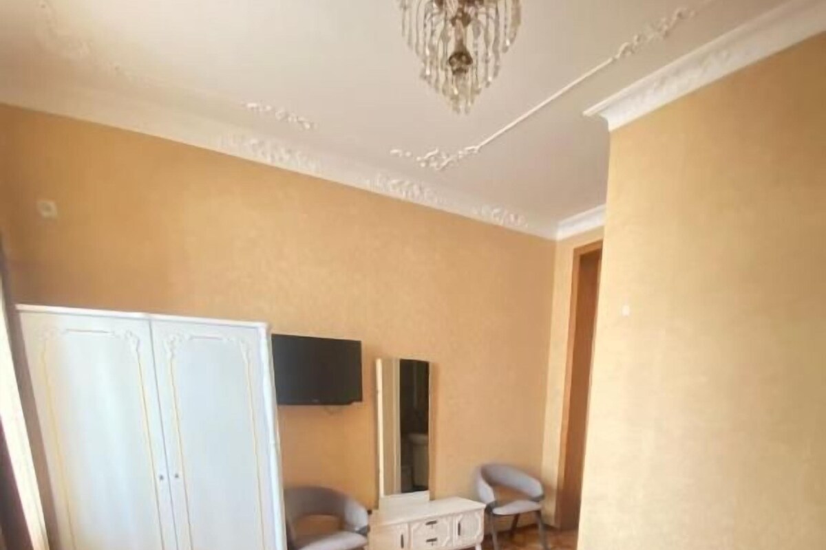 A hotel room with a bed, a wardrobe, a desk, and a chair.
