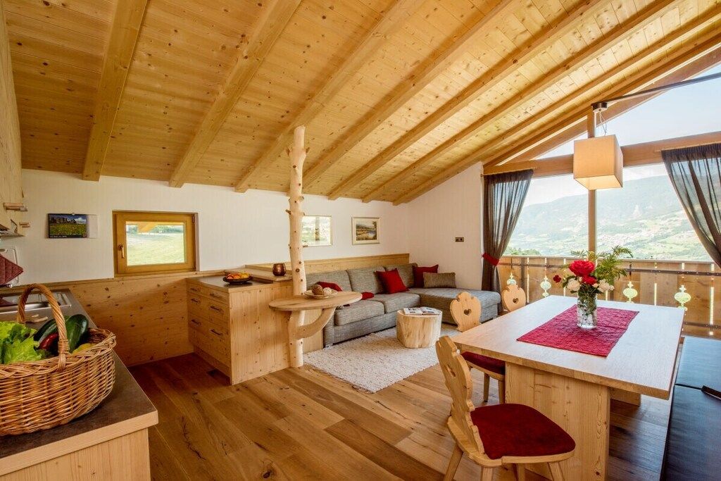 Ein Holzinterieur mit Esstisch, Stühlen, einer Couch und einer Küchenzeile.