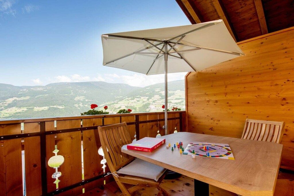 Eine Holzterrasse mit Tisch, Stühlen und Sonnenschirm.