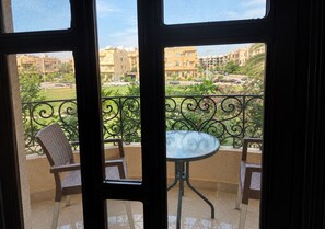 Ein Balkon mit Tisch und zwei Stühlen, der auf einen Wohnbereich mit Gebäuden und Grünflächen blickt.