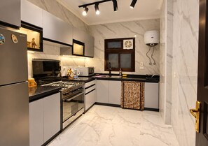 A modern kitchen with a gas stove, microwave, and a built-in oven. - Luxury Apartment in New Cairo (Cairo Governorate)