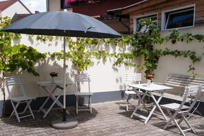 An outdoor patio with a table and chairs, an umbrella, and a wall with climbing plants. - Holiday apartment with 3 bedrooms (Freinsheim)