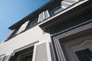 A building facade with a symmetrical window design, a door with decorative molding, and a clear sky in the background. - Holiday apartment with 3 bedrooms (Freinsheim)