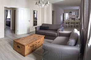 A living room with a grey sofa, a wooden chest, and a chandelier. - Holiday apartment with 3 bedrooms (Freinsheim)