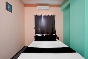 Una habitación pequeña con una cama, una cortina, un equipo de aire acondicionado y una puerta.