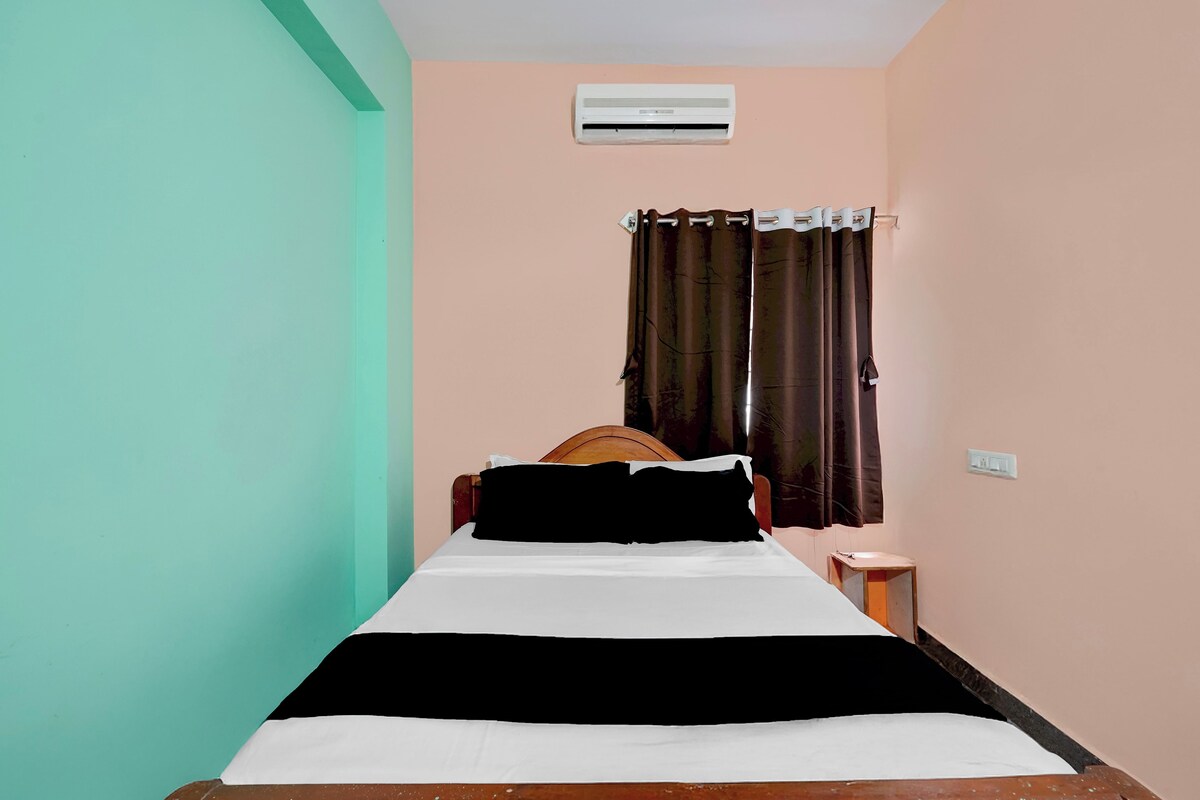 Una cama individual con cabecera de madera, una mesita de noche y un aire acondicionado de pared.