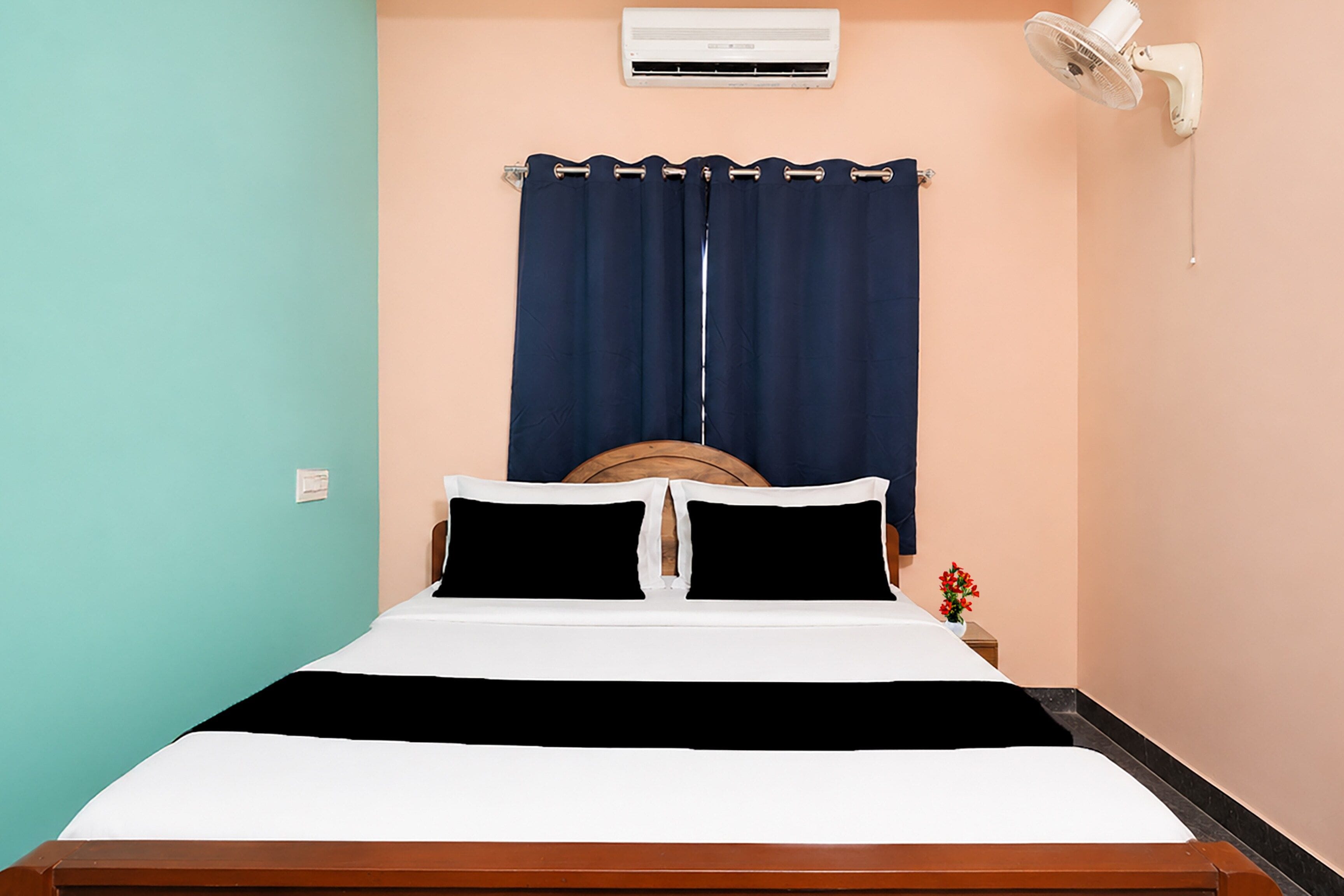 Un letto con testiera in legno, materasso bianco e tende blu scuro.