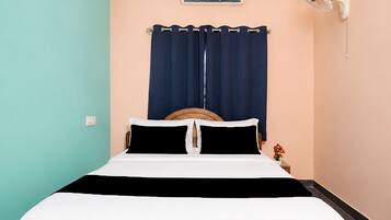 Un letto con testiera in legno, materasso bianco e tende blu scuro.