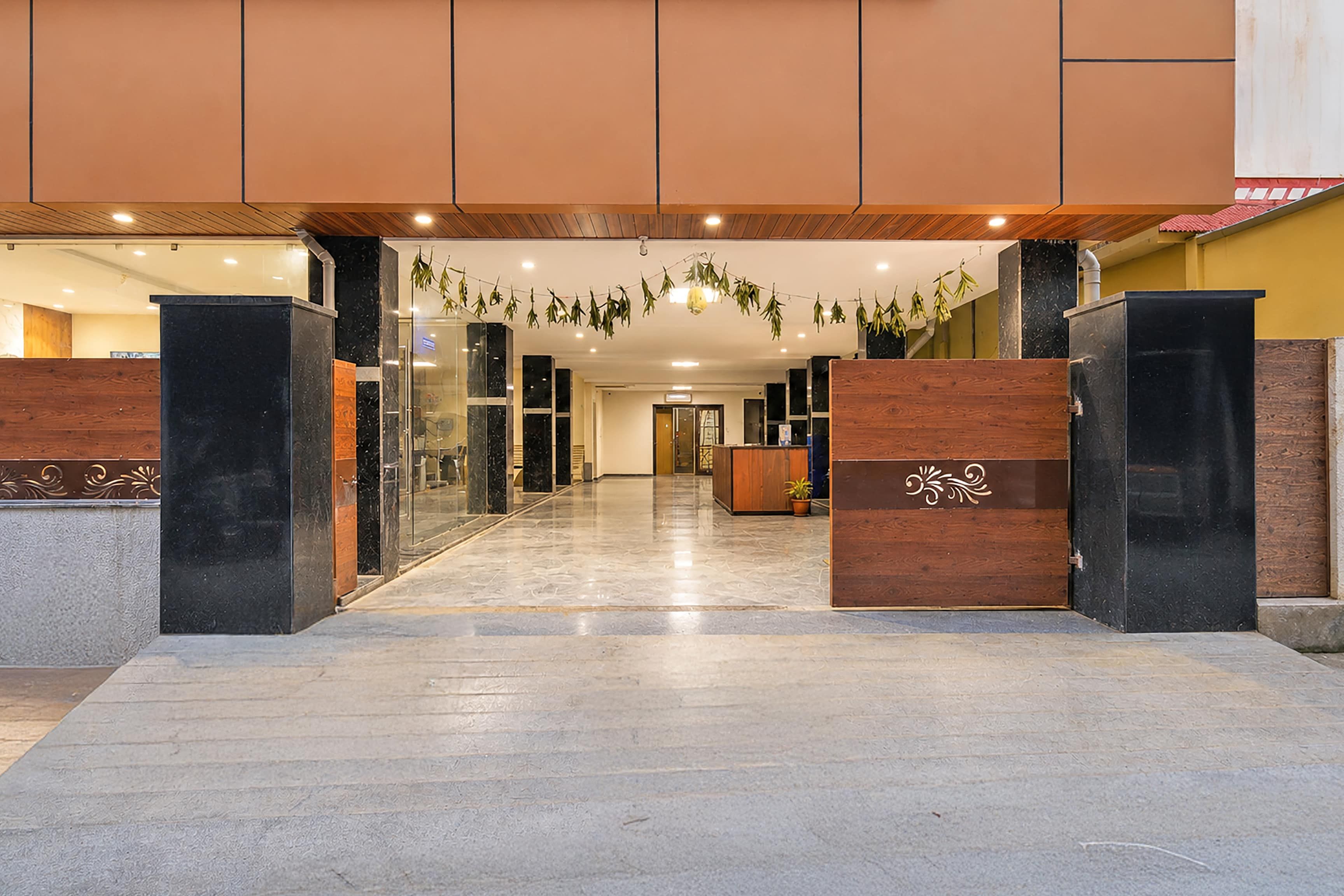 Een hotel lobby met een receptiebalie, glazen deuren en een betegelde vloer.
