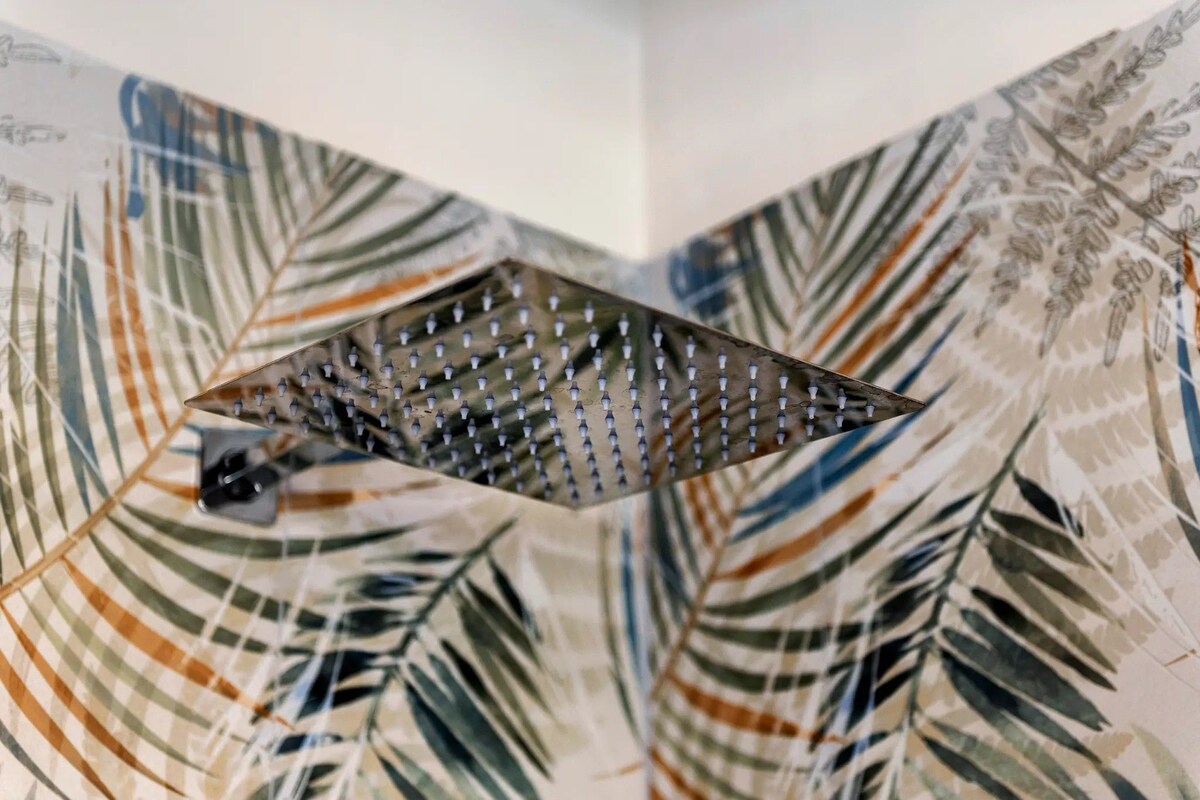 A corner of a room with a patterned wallpaper featuring leaf designs.