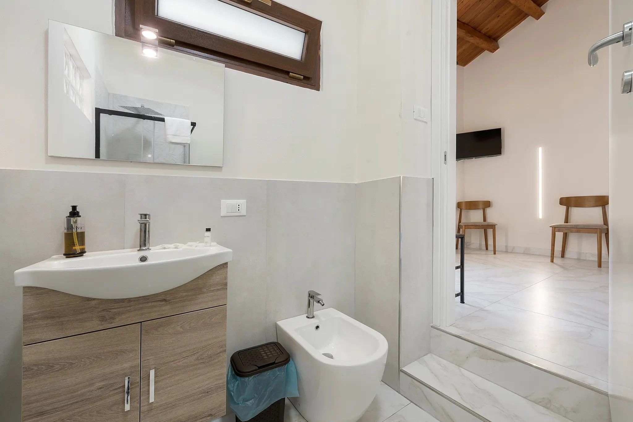 Une salle de bain avec un lavabo blanc, un bidet et un miroir au-dessus du lavabo.