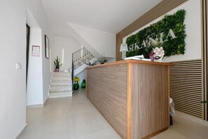 A reception area with a wooden reception desk, a staircase, and a wall-mounted sign. - Sikania agri relais (Caccamo)