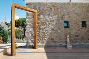 Un muro de piedra con estructura de madera, una pequeña ventana y un caño de piedra.
