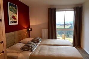 Ein Doppelbett mit Kopfteil, ein Poster an der Wand, ein Fenster mit Vorhängen und Blick ins Freie.