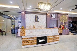 Un mostrador de recepción con encimera de mármol, un reloj y un letrero que indica 'OWNHOUSE OYO-Serviced'.