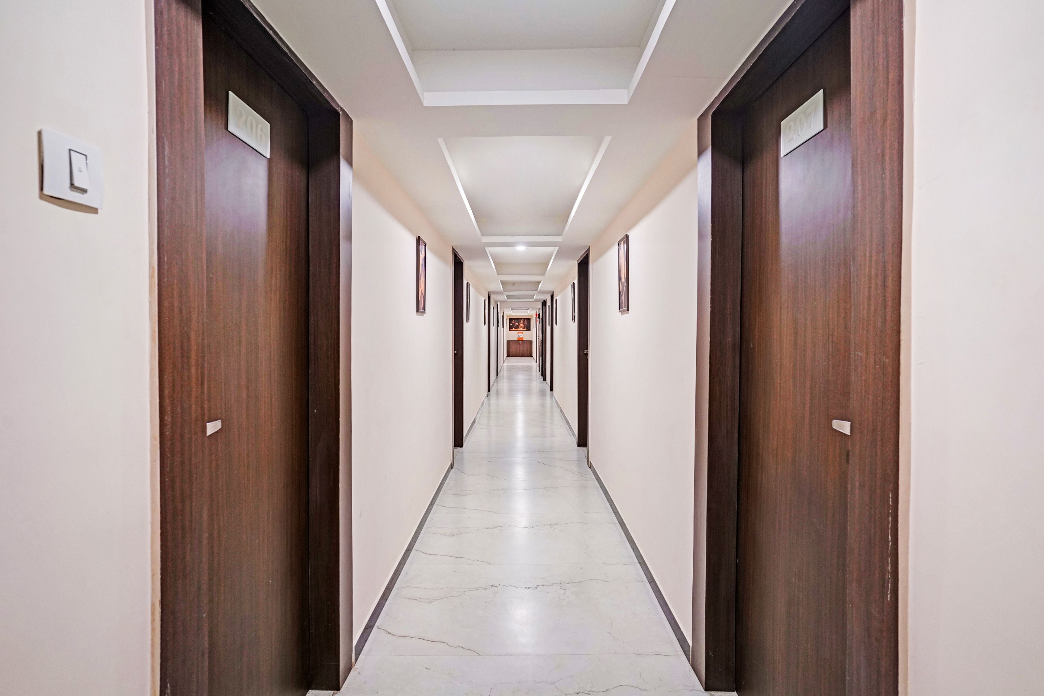 Un largo y estrecho pasillo de hotel con puertas de madera a ambos lados y suelo de baldosas.