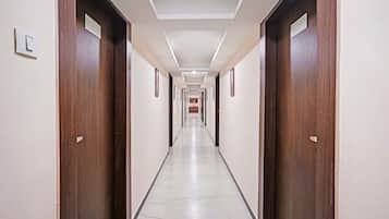 Un largo y estrecho pasillo de hotel con puertas de madera a ambos lados y suelo de baldosas.