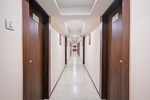 Un largo y estrecho pasillo de hotel con puertas de madera a ambos lados y suelo de baldosas.