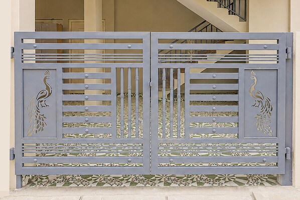 Una reja azul de metal con motivos de pavo real y diseños geométricos.