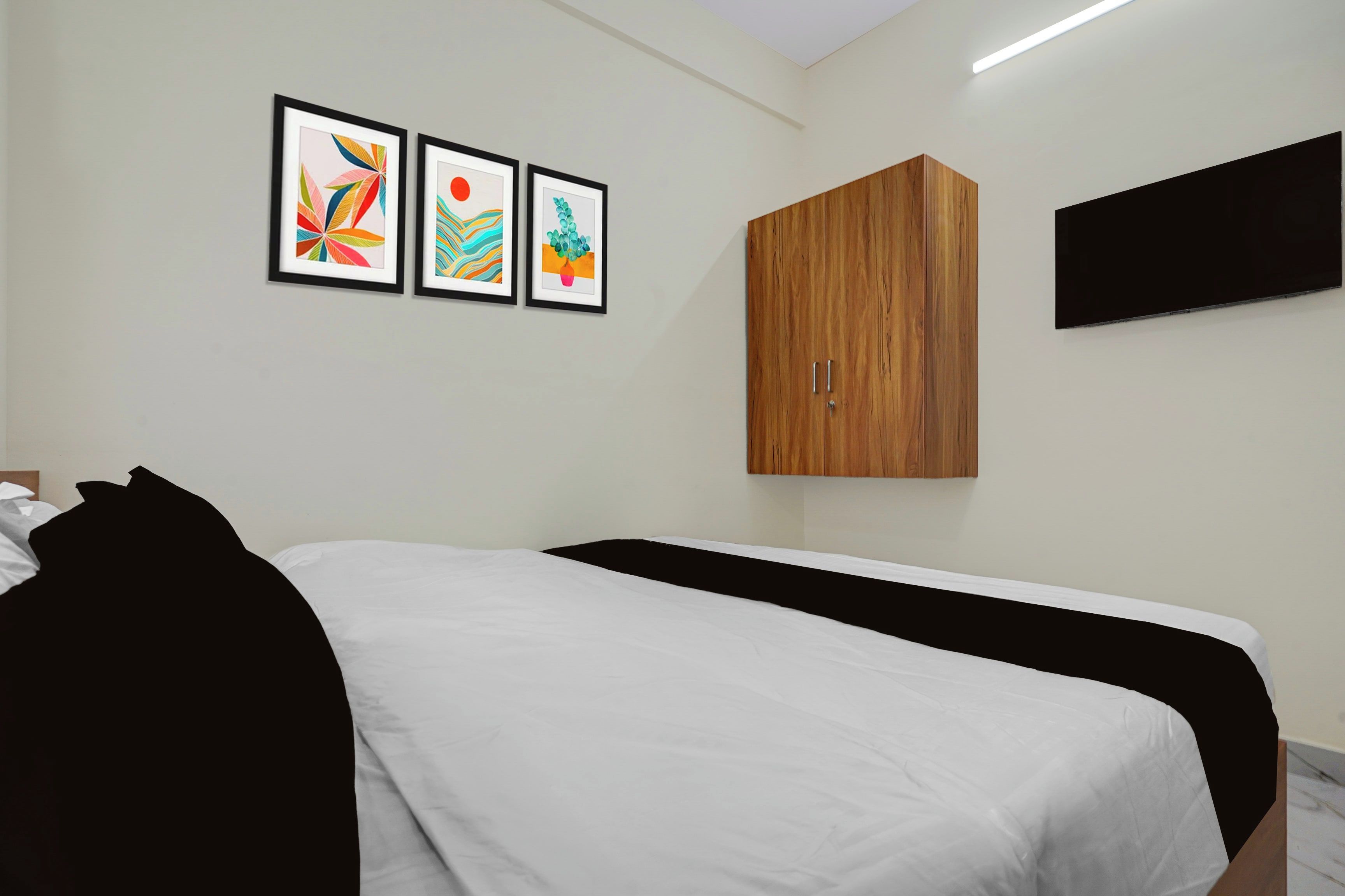 Una habitación de hotel con una cama, un armario y tres obras de arte enmarcadas en la pared.
