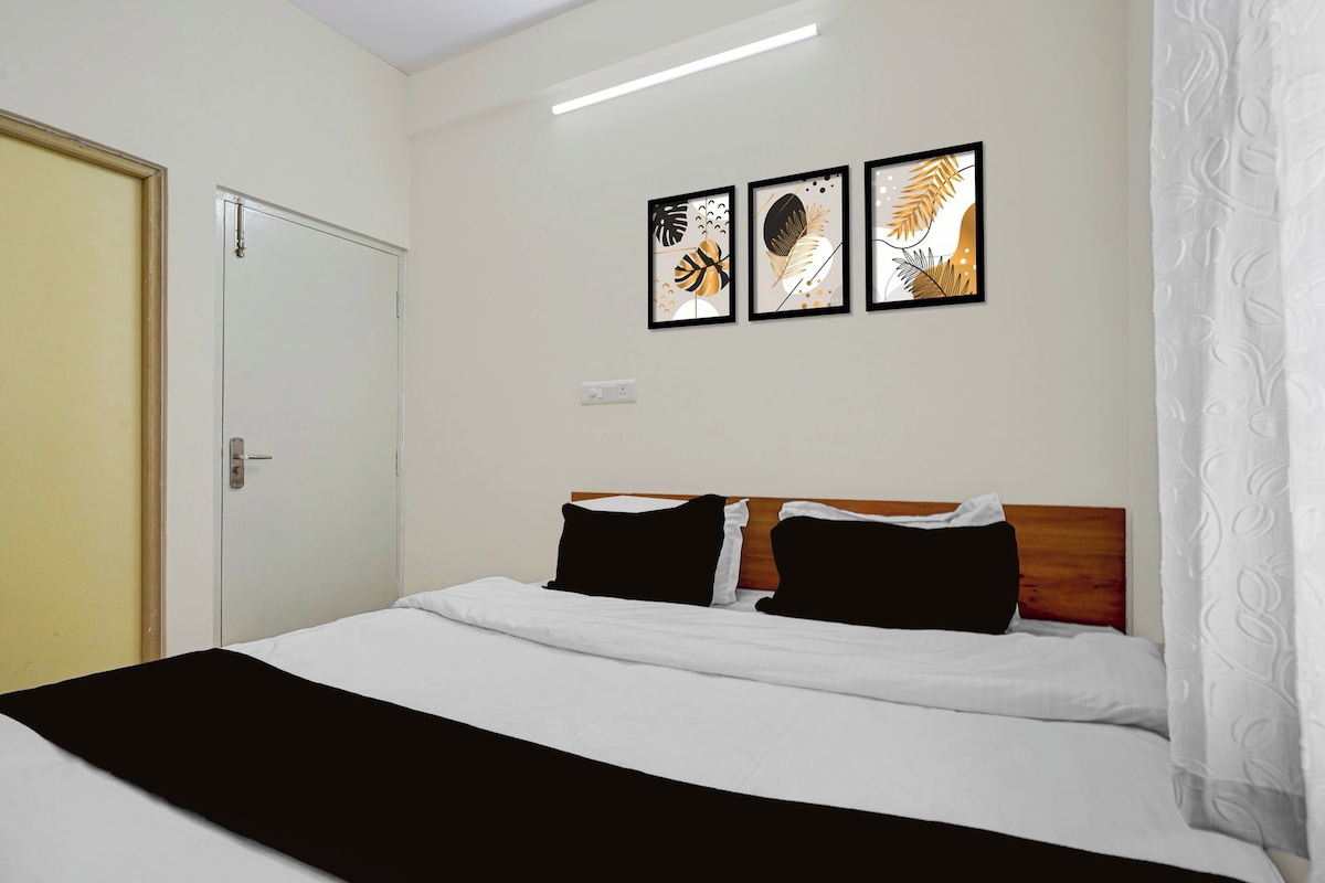 Una habitación de hotel con una cama, una puerta y tres cuadros enmarcados en la pared.