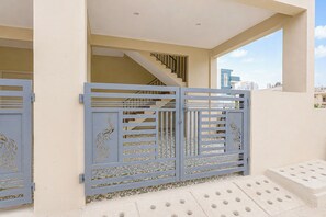 A gated entrance with decorative metalwork, a staircase leading to an upper level, and a view of a cityscape through a window. - Hotel O Bidarahalli Main Road (Bangalore)