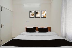 Una habitación de hotel con una cama, una puerta y tres obras de arte enmarcadas en la pared.