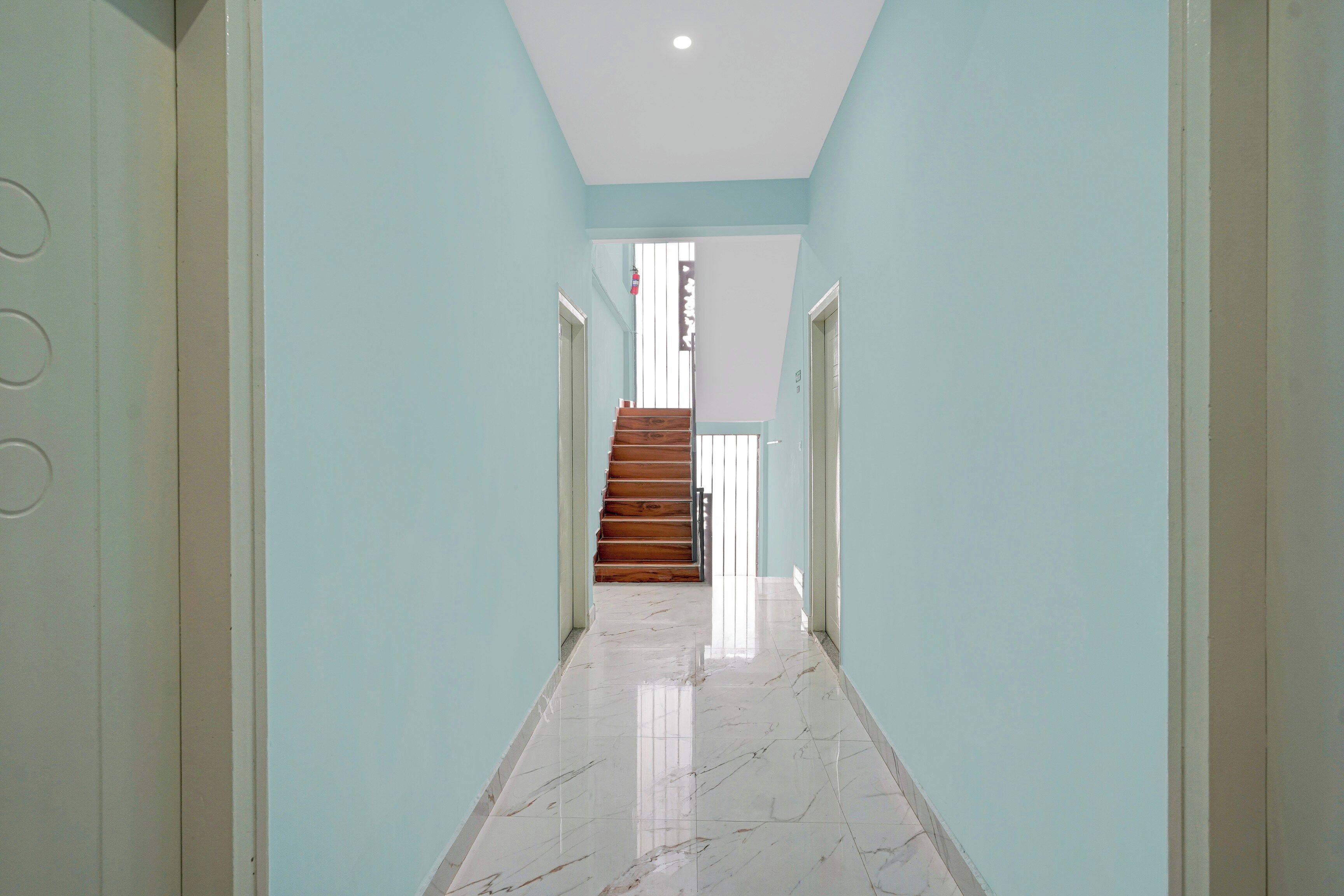 Un pasillo con piso de mármol que conduce a una escalera de madera.