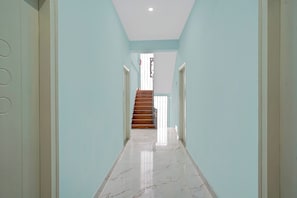 Un pasillo con piso de mármol que conduce a una escalera de madera.