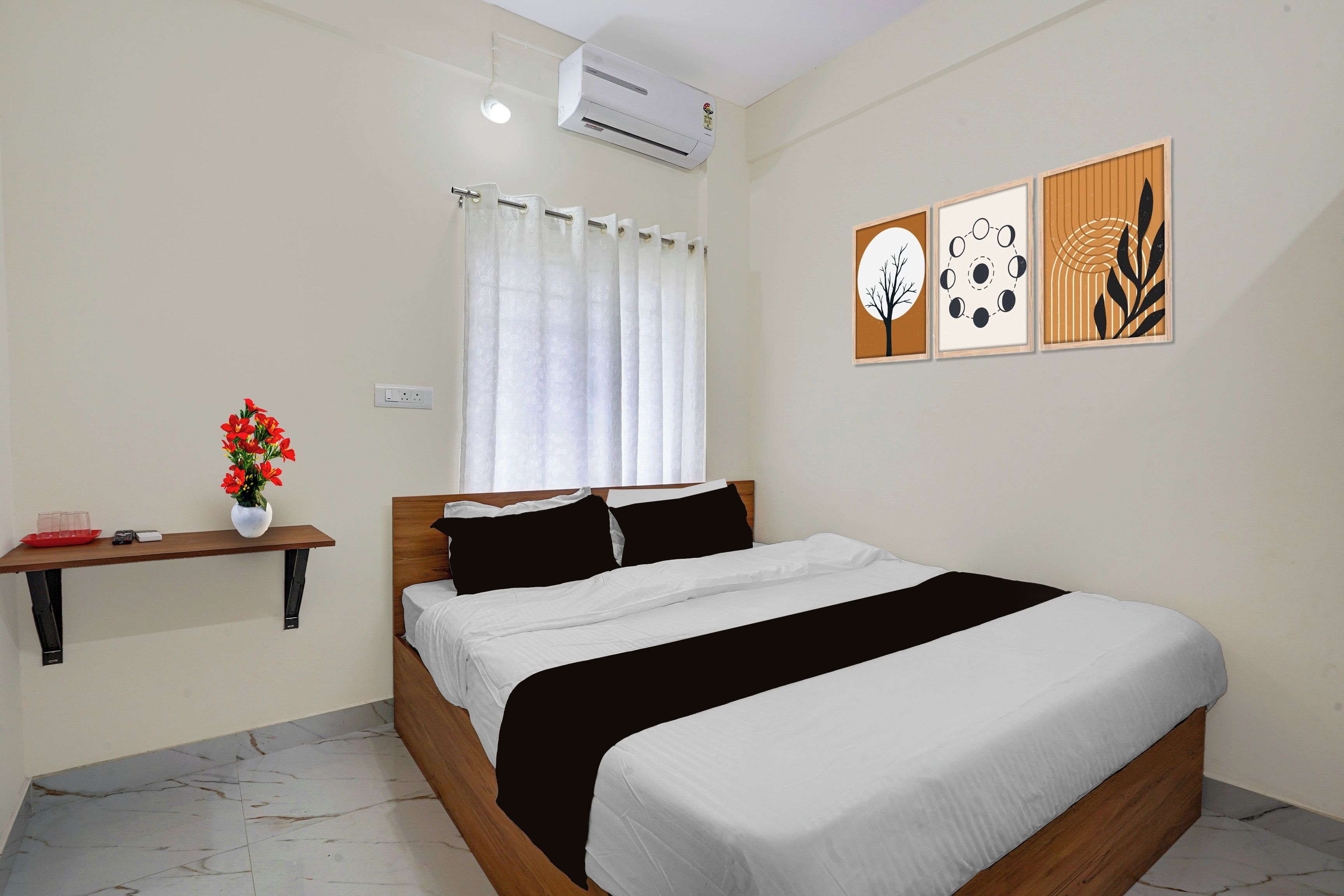 A bedroom with a bed, a nightstand, a window with curtains, an air conditioner, and wall art.