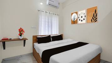 A bedroom with a bed, a nightstand, a window with curtains, an air conditioner, and wall art.