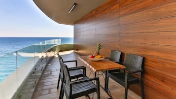 Un balcone con parete in legno, un tavolo con sedie e una ciotola di frutta.