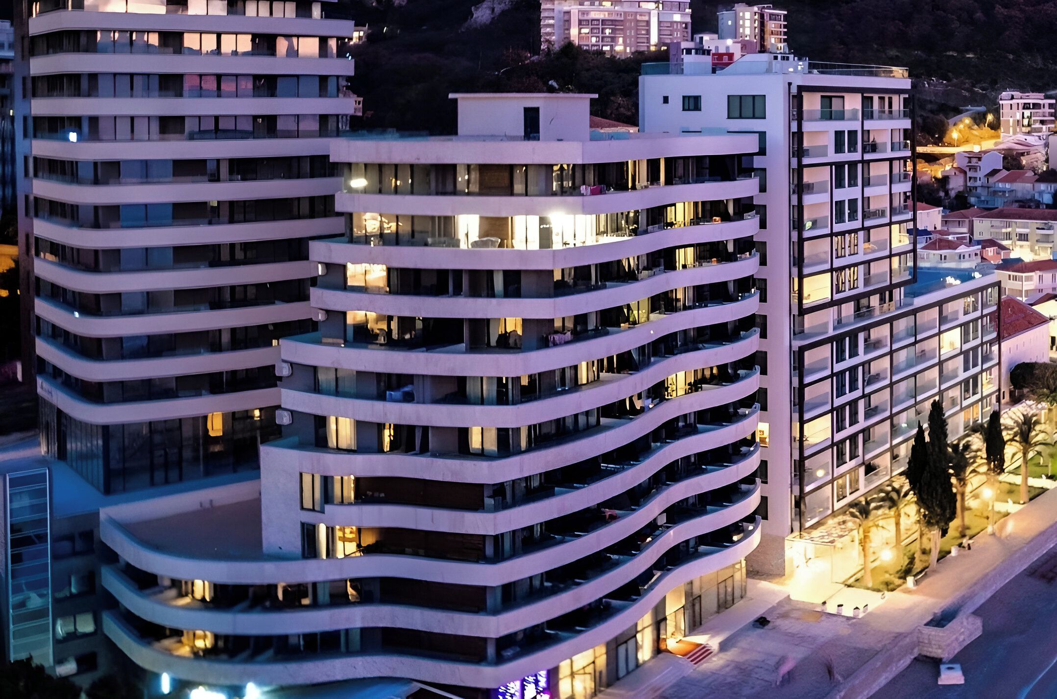 Ett hotell med flera våningar, balkonger, ett poolområde och utsikt över de omgivande byggnaderna.