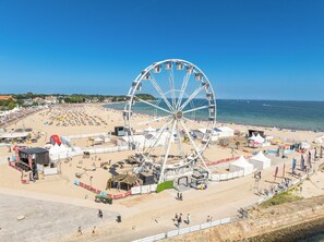 En strand med et stort pariserhjul, telte og en scene.