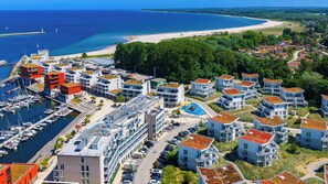Et kystnært boligområde med moderne bygninger, en lystbådehavn og en strand.