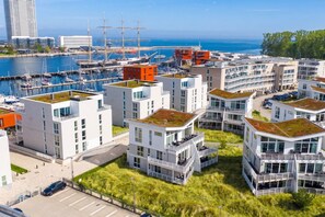 A modern residential area with multi-story buildings, green roofs, and a marina with sailboats. - Vrbo Property (Lübeck-Travemünde)