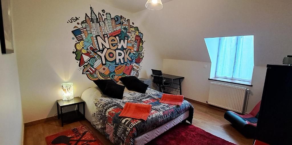 A bedroom with a bed, a wall mural, a desk, a chair, and a window.