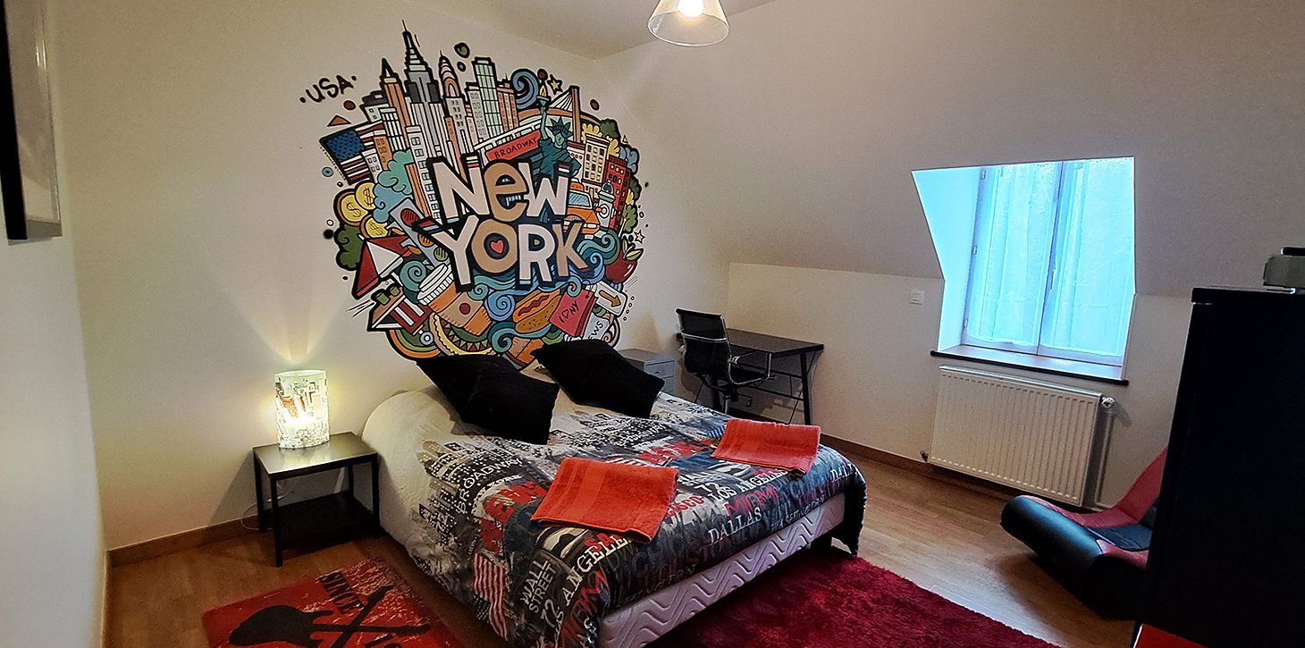 Une chambre à coucher comprenant un lit, un bureau, une chaise, une fenêtre et une fresque murale.