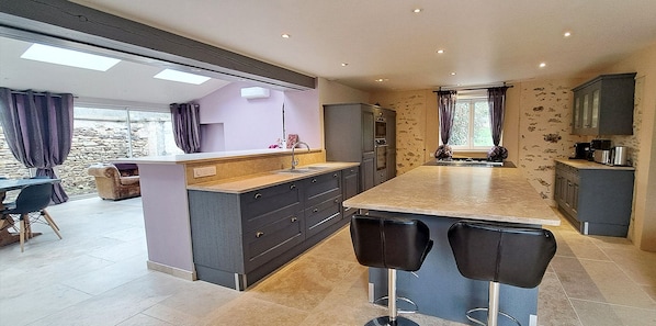 A modern kitchen with a central island, bar stools, and a dining area with a table and chairs.