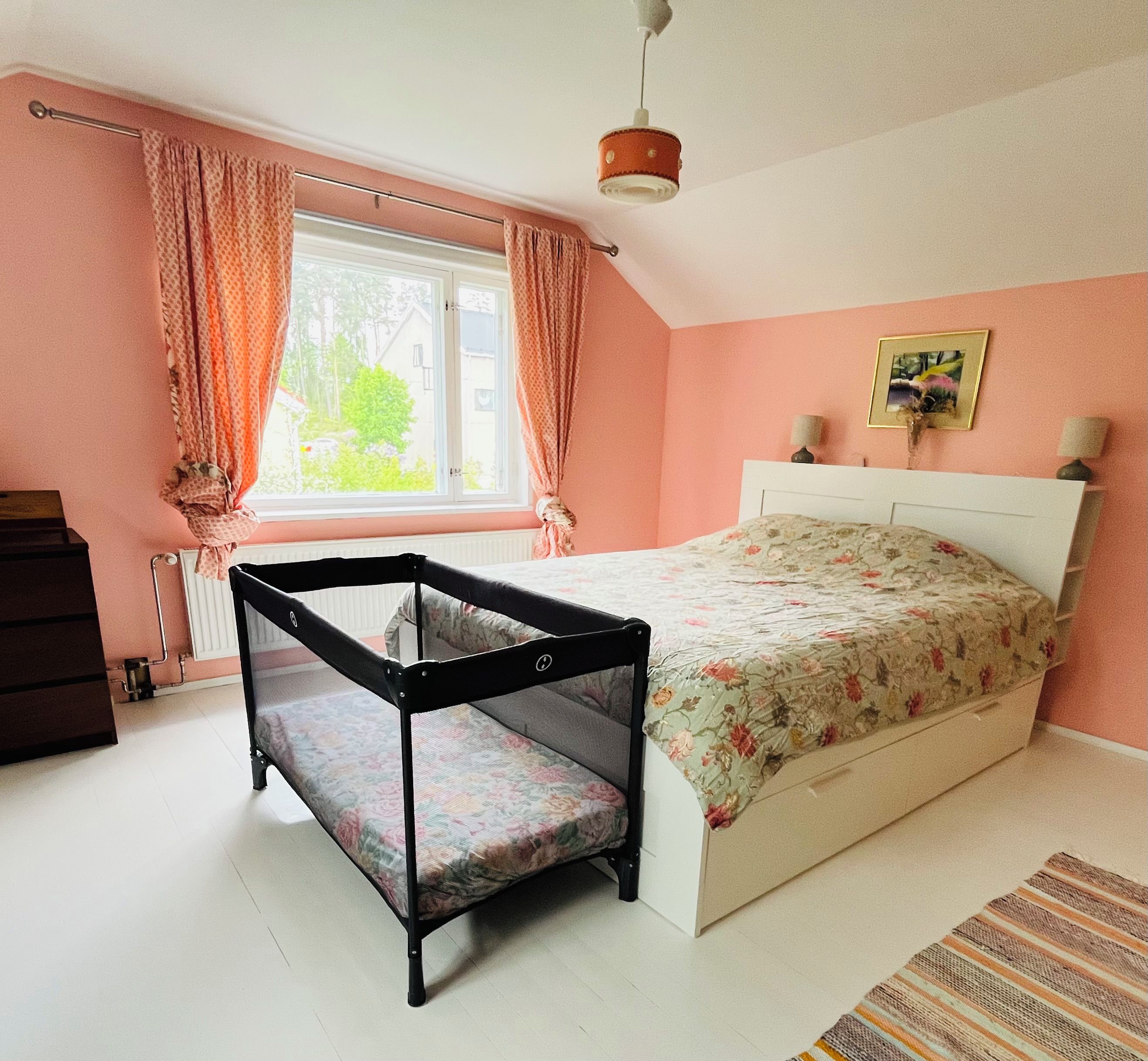 A bedroom with a bunk bed, a window with curtains, a bedside lamp, and a framed picture on the wall.